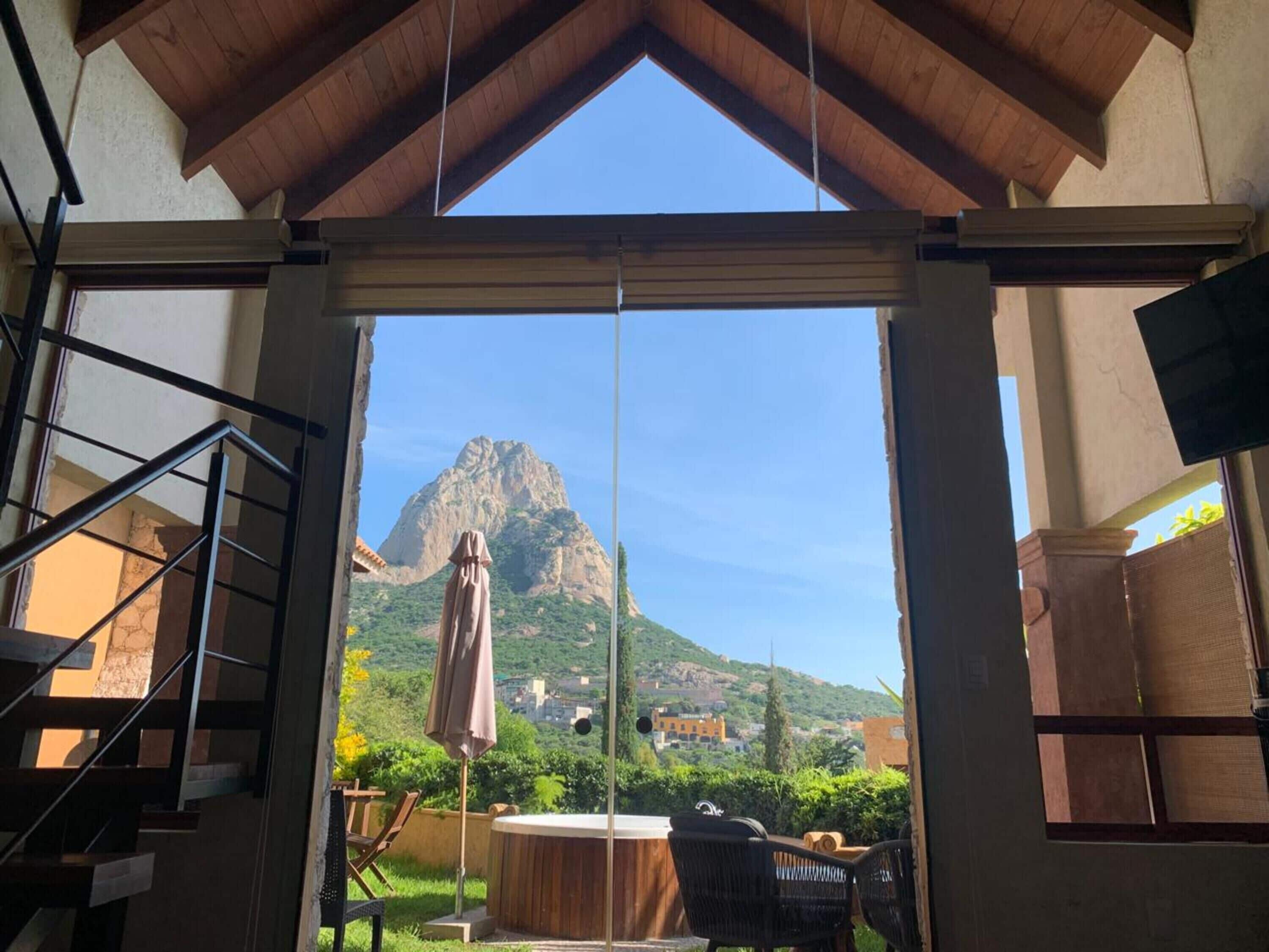 A room with a view of a mountain, a hot tub, and outdoor furniture.