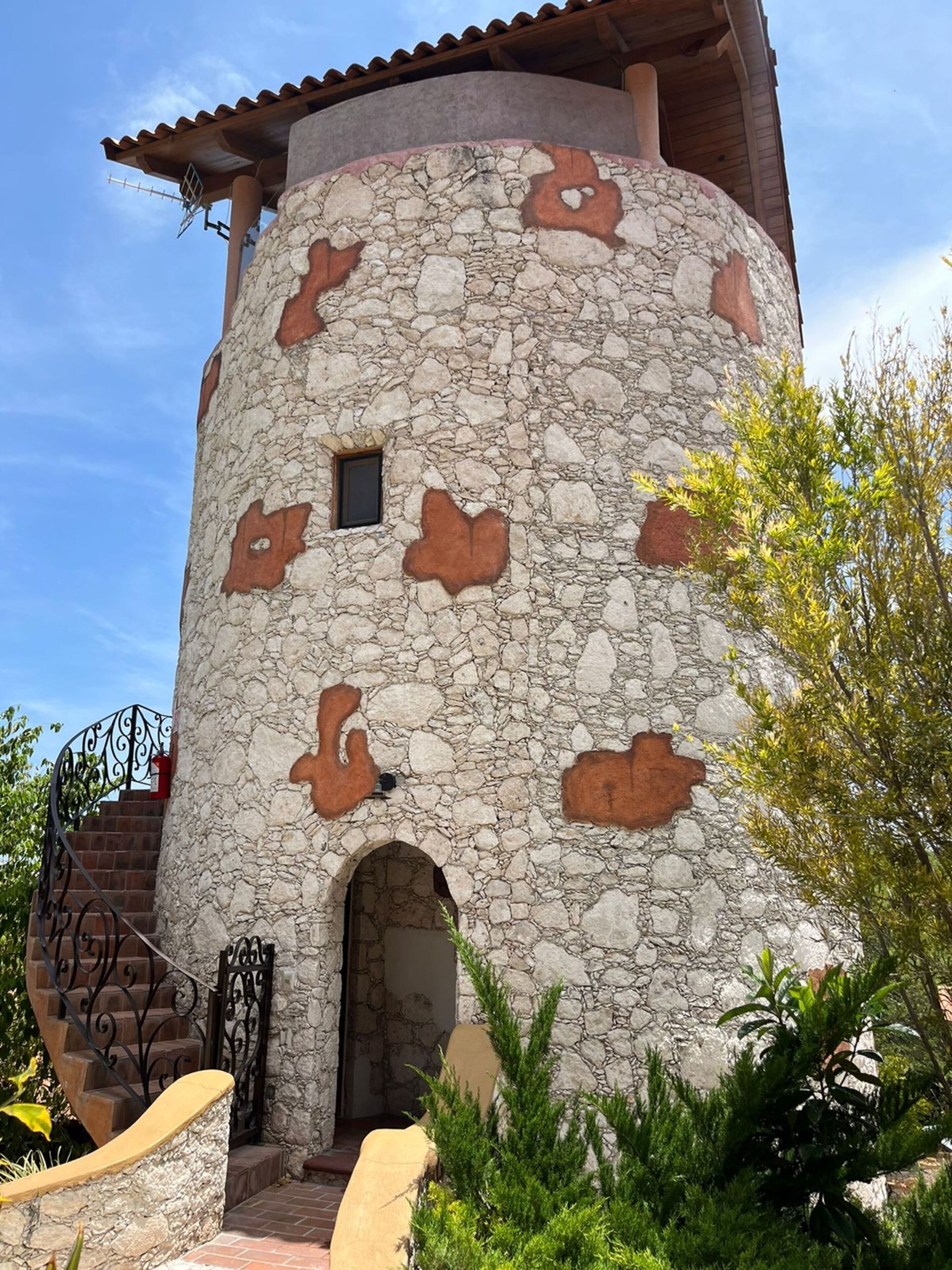 Un edificio de piedra con una torre circular, una ventana pequeña y una puerta.