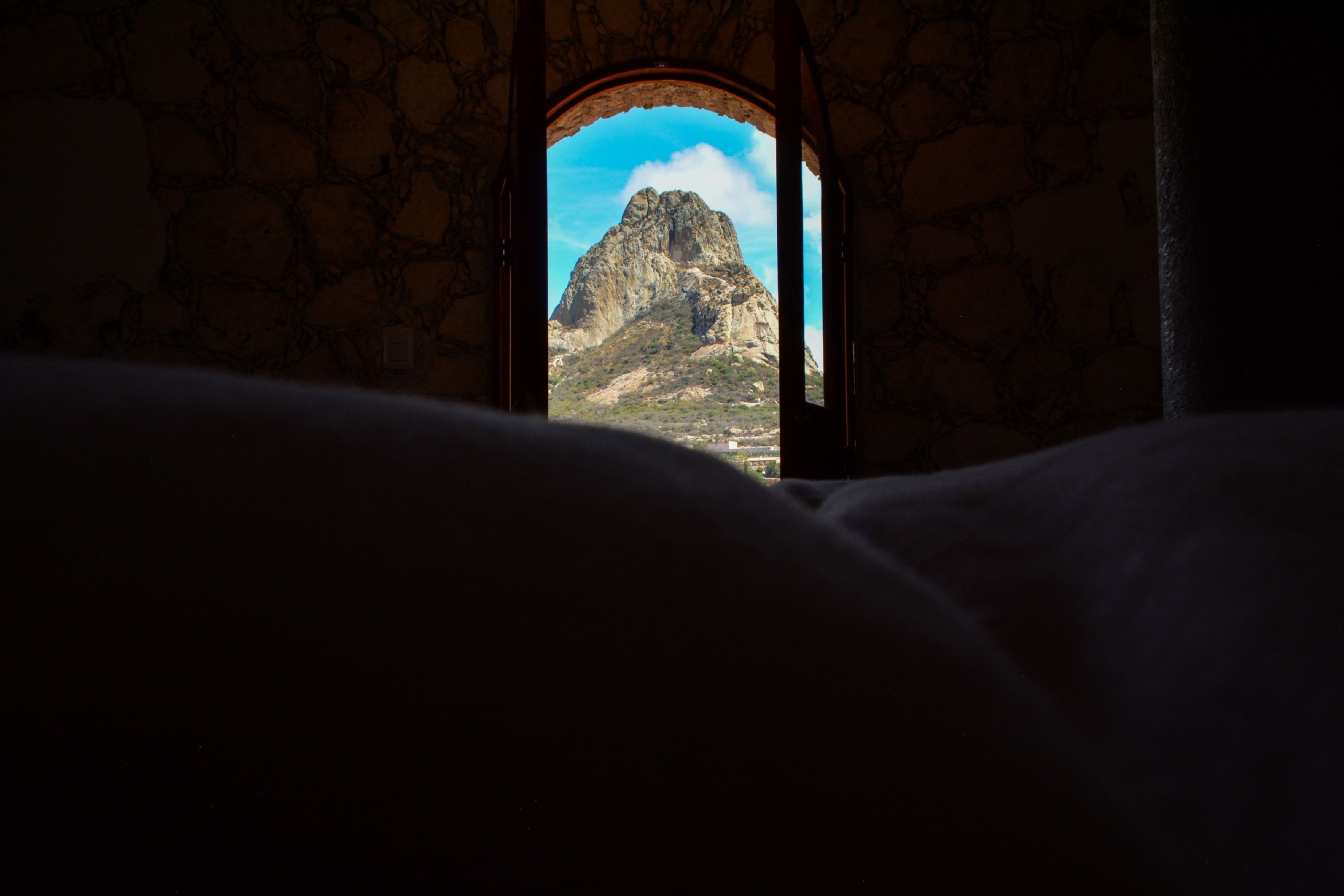 A stone wall with a window revealing a mountain view.