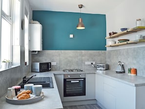 A modern kitchen with a teal accent wall, a gas stove, a built-in oven, a microwave, and a toaster.