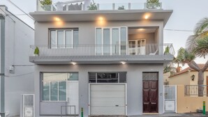 Ein modernes, zweistöckiges Gebäude mit Balkon, großen Fenstern und einer Garagentür.