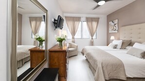 Ein Hotelzimmer mit einem großen Spiegel, einem Deckenventilator, einem Bett mit Kopfteil, einem Nachttisch mit Lampe und einem Sessel.
