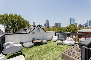A rooftop terrace with a view of a city skyline, featuring a wooden deck, seating area, and a small shed. - Modern Farmhouse with Rooftop Deck Downtown (Austin)