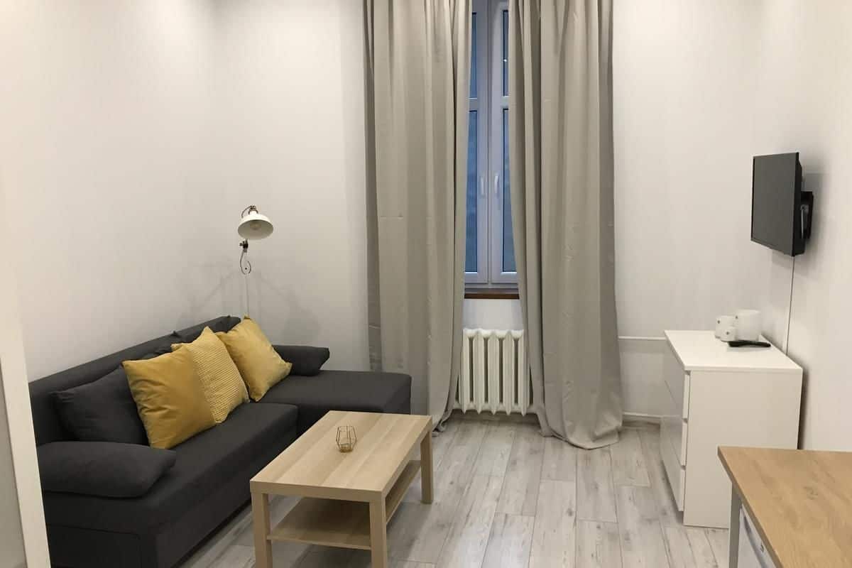 Ein modernes Wohnzimmer mit einer schwarzen Couch, einem Holztisch und einem weißen Schreibtisch.