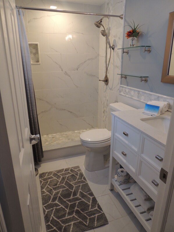 Un baño con ducha, inodoro y tocador.