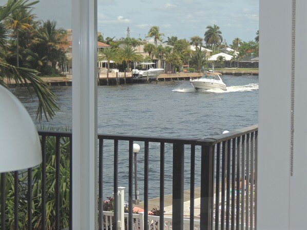 A view of a marina with a boat moving on the water, surrounded by palm trees and buildings. - Aqua Mar Condos (Pompano Beach)