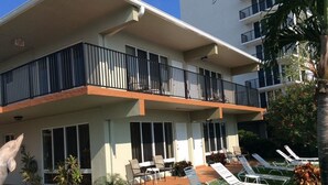 Et hotel med flere etager, balkon, udendørs siddepladser og liggestole.