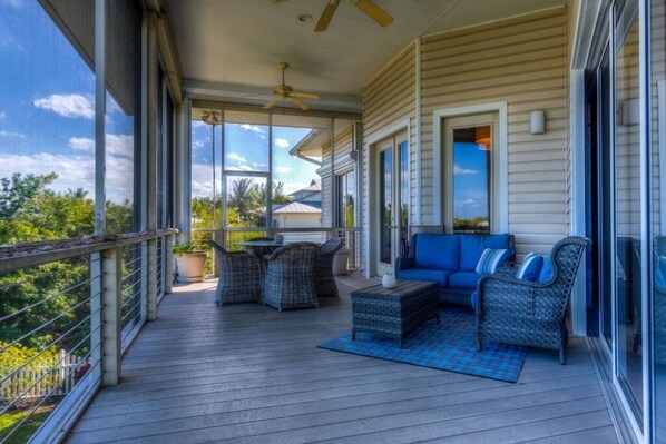 A covered porch with wicker furniture, a ceiling fan, and a view of the outdoors.