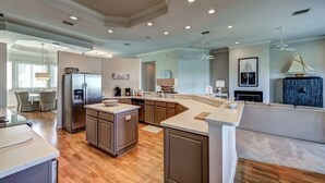 A spacious kitchen with a central island, wooden flooring, and modern appliances.