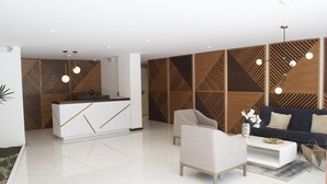 A modern reception area with a white reception desk, a sofa, and a coffee table. - SENSATIONAL APARTMENT FOR COUPLES/EXECUTIVES/SHORT FAMILY (Quito)