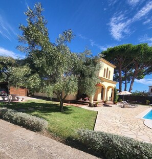 A villa with a swimming pool, outdoor seating, and a large tree. - Renovated Villa, PRIVATE LARGE LEVEL GARDEN & POOL, WIFI, TV, AIRCON IN BEDROOM  (Calonge)