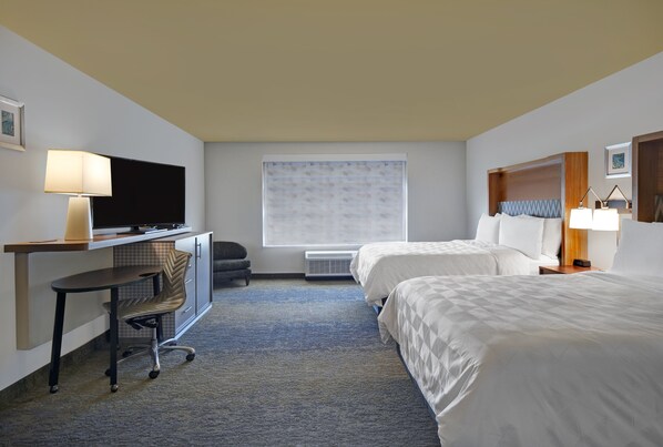 A hotel room with a desk, two beds, a TV, and a window with blinds. - Holiday Inn Grand Rapids North - Walker by IHG (Grand Rapids)
