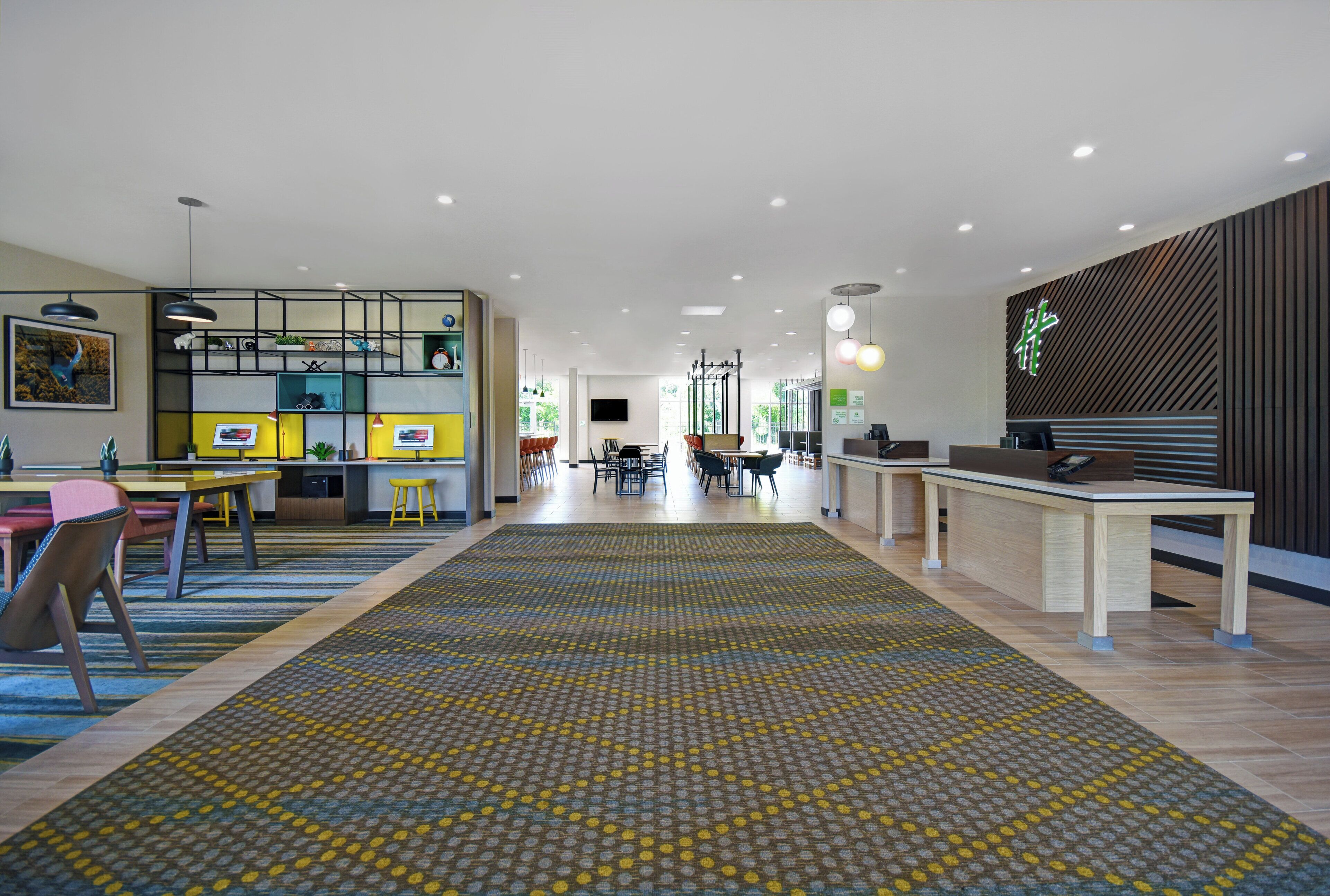 A spacious hotel lobby with a central seating area, a reception desk, and a patterned carpet.