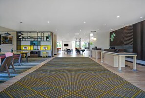 Un hall d’hôtel spacieux avec un espace salon central, un comptoir d’accueil et une moquette à motifs.