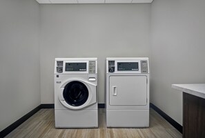 A laundry room with two front-loading washing machines and a dryer. - Holiday Inn Grand Rapids North - Walker by IHG (Grand Rapids)