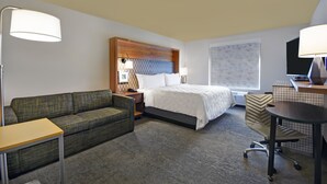 A hotel room with a bed, a sofa, a desk, and a chair. - Holiday Inn Grand Rapids North - Walker by IHG (Grand Rapids)