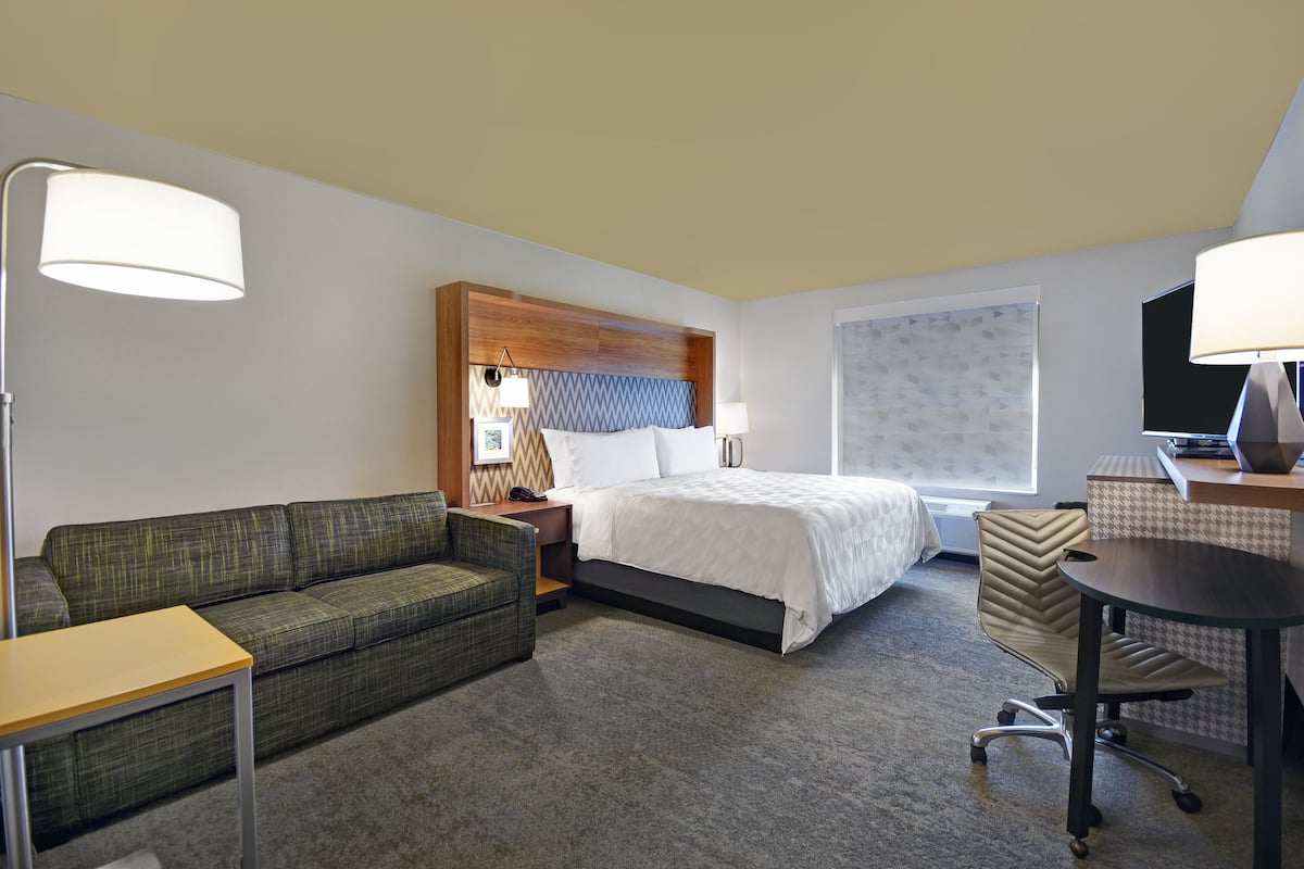 Une chambre d’hôtel avec un lit, un canapé, un bureau et une chaise.