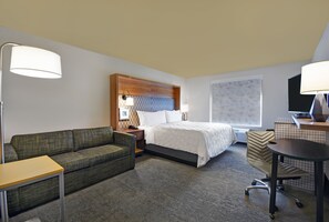 A hotel room with a bed, a sofa, a desk, and a chair. - Holiday Inn Grand Rapids North - Walker by IHG (Grand Rapids)