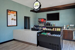 A breakfast area with a menu board, a Coca-Cola vending machine, and a refrigerated display of beverages. - Holiday Inn Grand Rapids North - Walker by IHG (Grand Rapids)