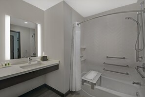 A modern bathroom with a large mirror, a sink, a shower with a glass door, and a small towel rack. - Holiday Inn Grand Rapids North - Walker by IHG (Grand Rapids)