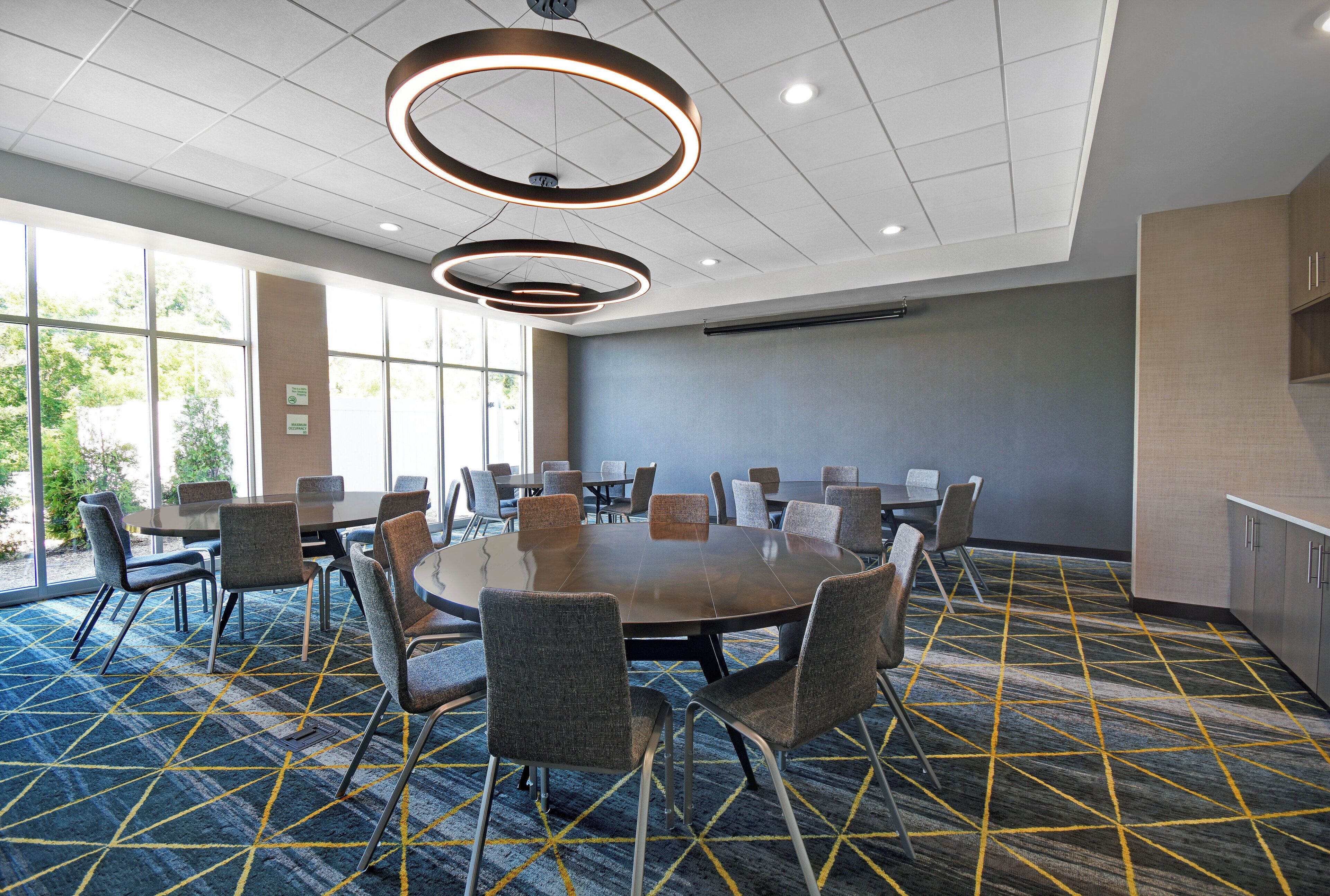 A conference room with a large table, chairs, and a modern ceiling light fixture.