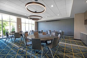 Une salle de conférence dotée d’une grande table, de chaises et d’un luminaire moderne au plafond.