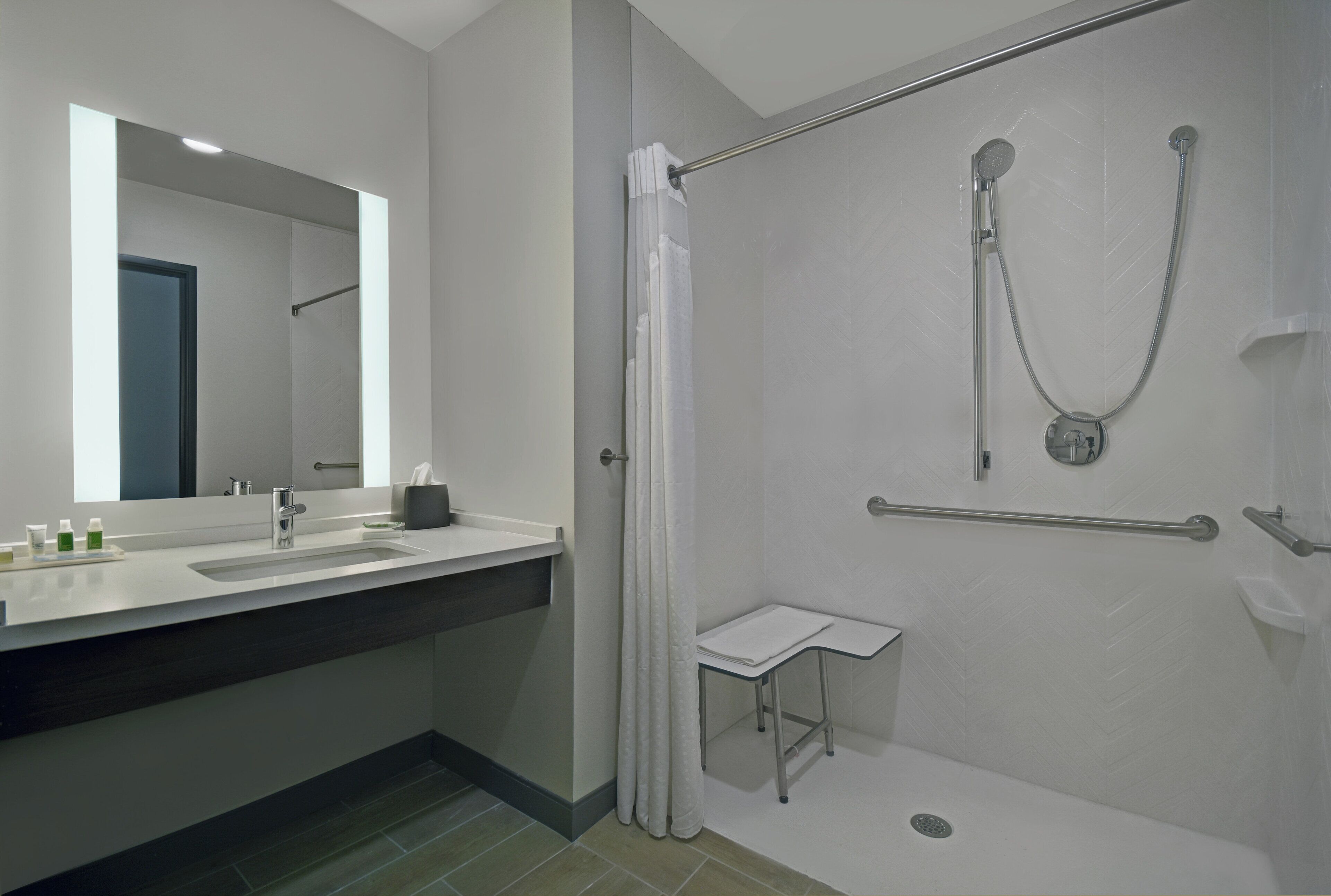 Une salle de bain moderne avec une douche, un lavabo et un miroir.