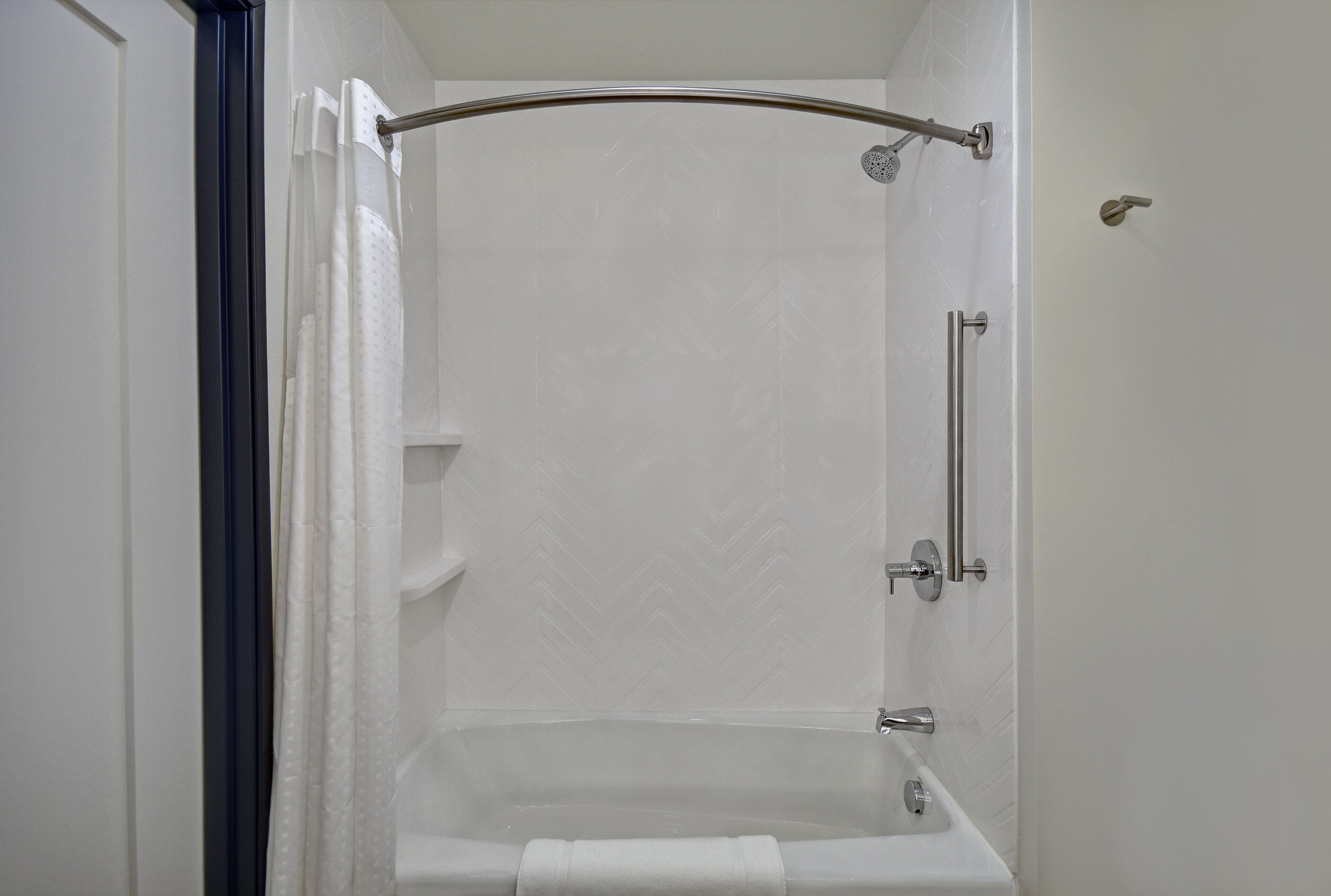 A walk-in shower with a glass door, a handheld showerhead, and a handheld shower bar.
