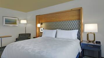 A hotel room with a bed, two bedside tables, a chair, a lamp, and a painting on the wall.