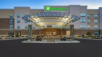 A Holiday Inn hotel entrance with a covered walkway and large planters.