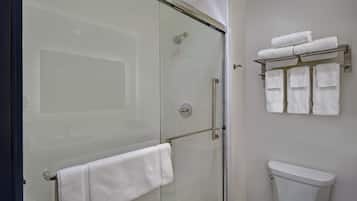Une douche fermée par des parois en verre, avec un porte-serviettes et des toilettes sur lesquelles est placé un autre porte-serviettes.