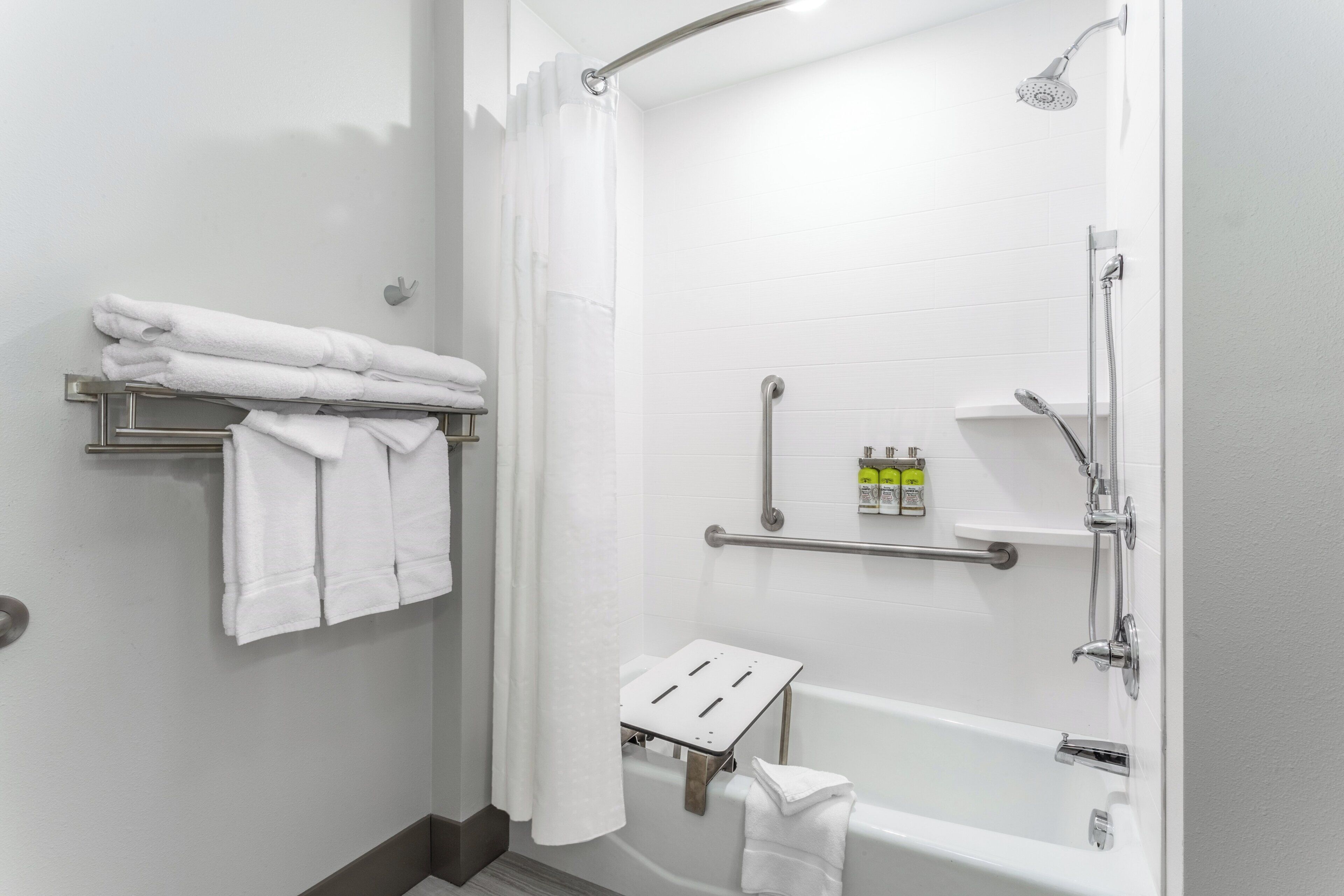 A modern bathroom with a walk-in shower, a bathtub, and a towel rack with folded towels.