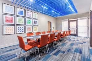A conference room with a long table, orange chairs, and framed artwork on the walls. - Holiday Inn Express & Suites Kearney by IHG (Kearney)