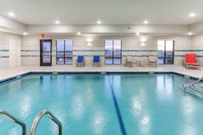 Une piscine intérieure donnant sur un paysage grâce aux grandes fenêtres.