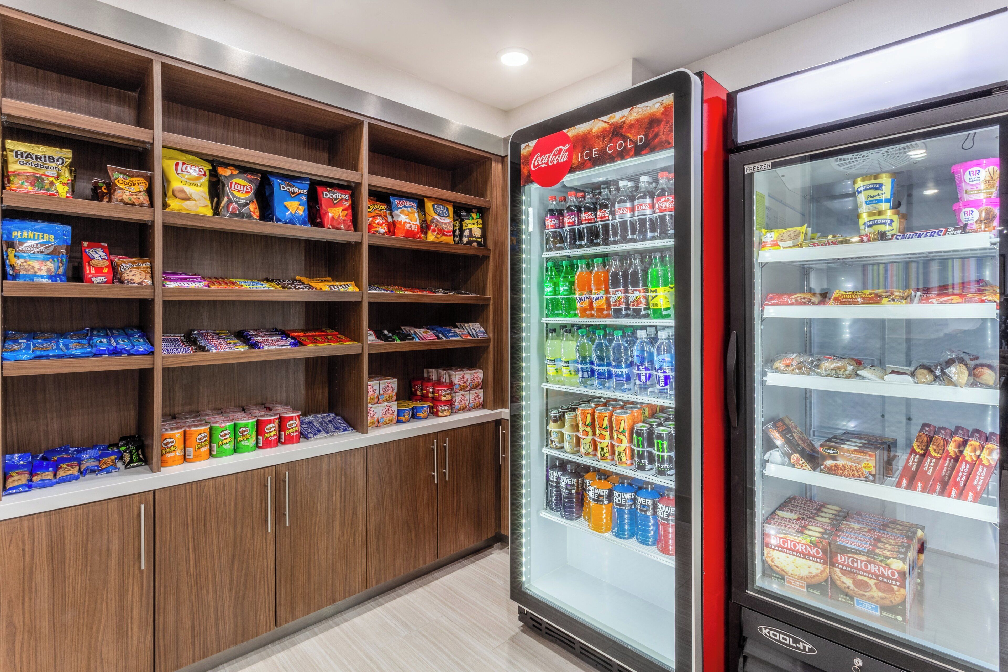 A snack and beverage vending area with various snack options and a Coca-Cola refrigerator.