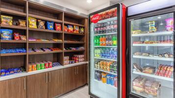 A snack and beverage vending area with various snack options and a Coca-Cola refrigerator.