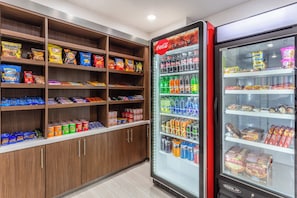 Zona de venta automática con bebidas y aperitivos, que incluye una nevera de Coca-Cola.