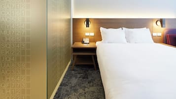 Ein Hotelzimmer mit einem Bett, Nachttischen, einem Telefon und einer Wand mit Zimmernummern.