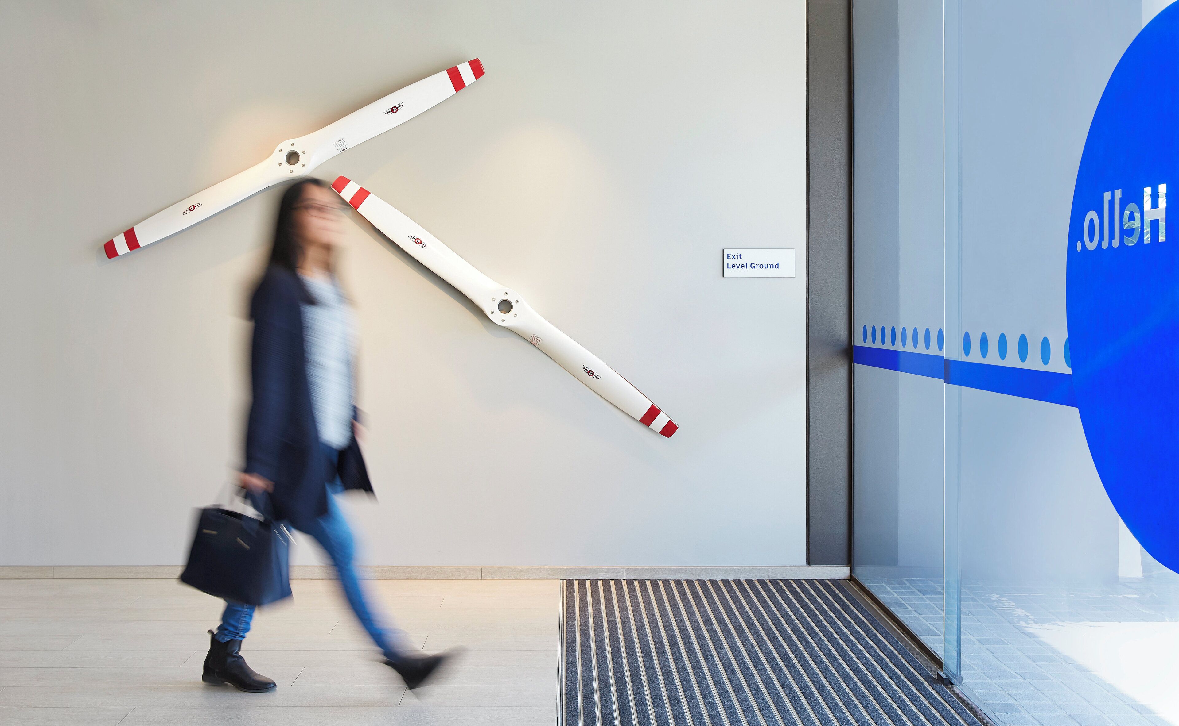 A person walking past a wall with a large, white and red object resembling a door or barrier.