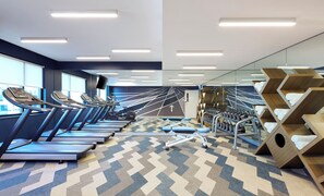 Ett gym med löpband, motionscyklar och en vägg täckt med speglar.