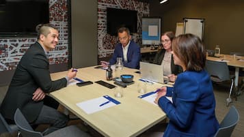 A conference room with a long table, chairs, a projector screen, and a whiteboard.