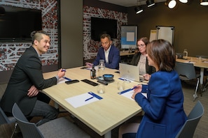 A conference room with a long table, chairs, a projector screen, and a whiteboard. - Holiday Inn Express Sydney Airport by IHG (Mascot)