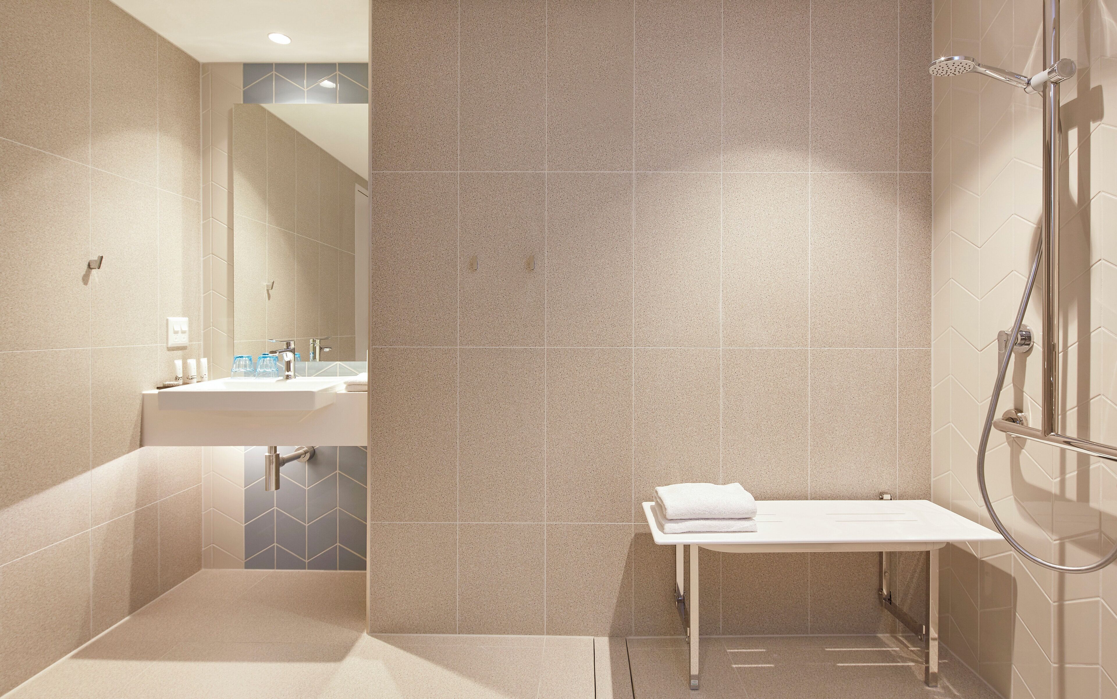 A modern bathroom with a shower, a sink, and a mirror.