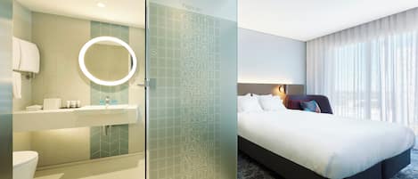 Habitación de hotel con cama, baño con espejo y puerta de vidrio con números de vuelo.