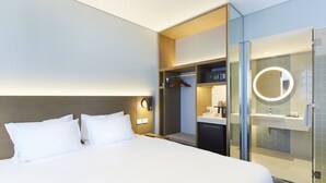 A hotel room with a large bed, a bedside table, a built-in wardrobe, a shower area, and a round mirror. - Holiday Inn Express Sydney Airport by IHG (Mascot)