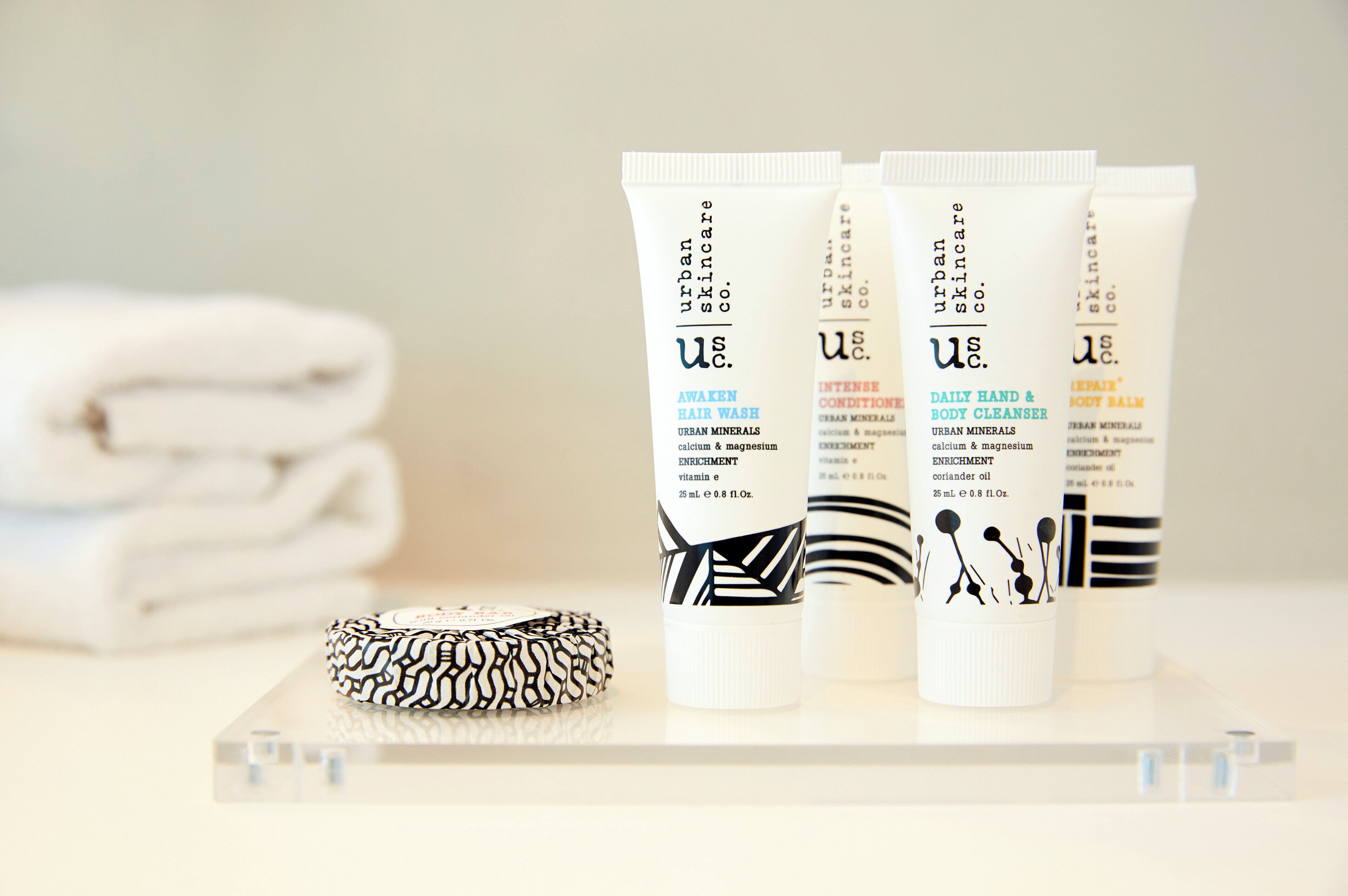 Tres tubos de productos Urban Minerals sobre una superficie transparente con un objeto estampado a un lado.