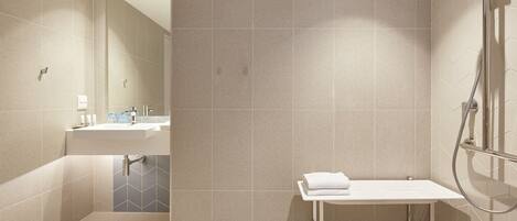 A modern bathroom with a shower, sink, and a small table with a towel.