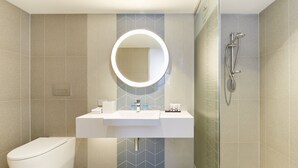 A modern bathroom with a white sink, a round mirror, a toilet, and a shower area. - Holiday Inn Express Sydney Airport by IHG (Mascot)