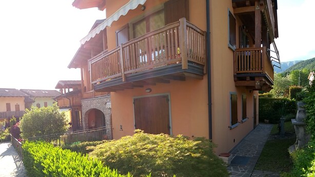 Ein zweistöckiges Gebäude mit Balkon, steinernen Bogen und einem gepflegten Garten.