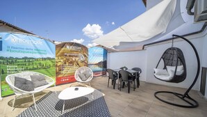 An outdoor seating area with a hanging chair, a round table, and a patterned rug. - Boutique Apartment Eleganza (Chiusi Scalo)
